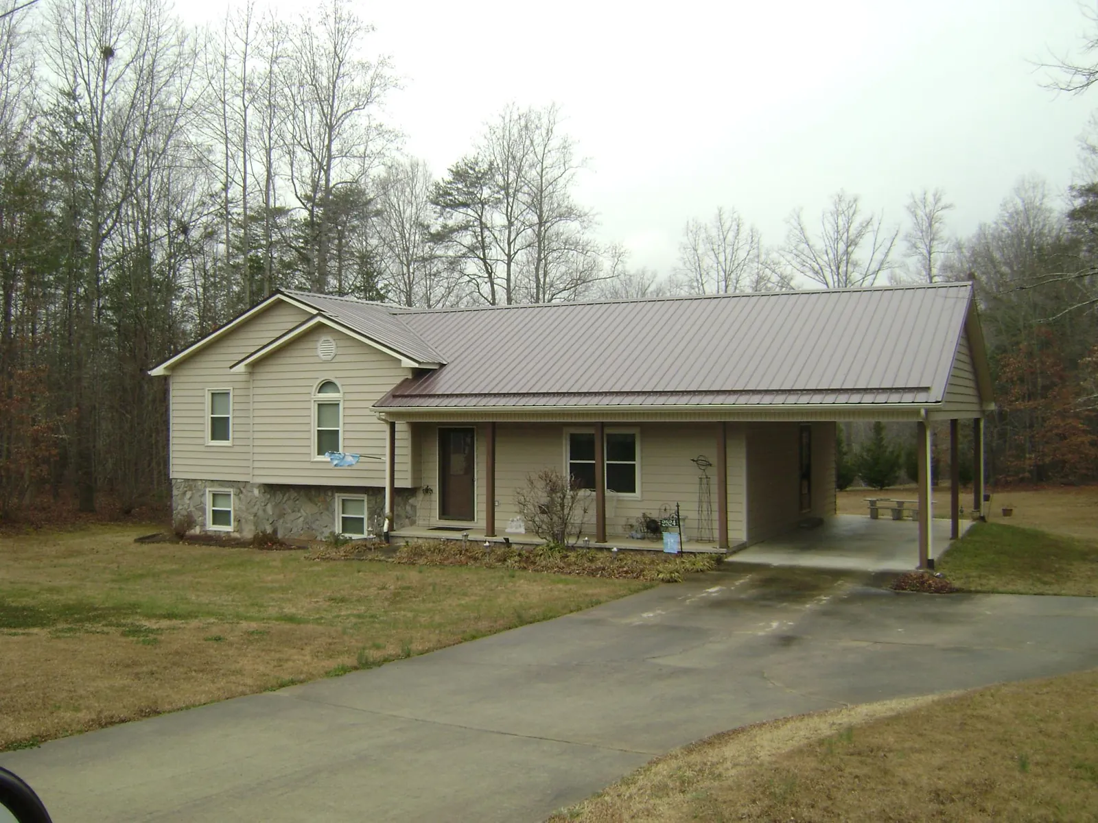 Brown metal roof on a tan split level home with an attached carport in Canton
